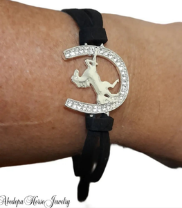 Horse-shoe bracelet with silver-plated metal and crystals, featuring a rearing horse on a black cord.