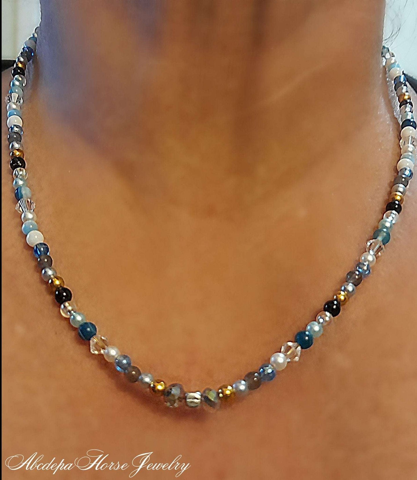 Blue Agate Crystal Horseshoe Necklace on neck, featuring beaded design with white howlite, blue agate, gold hematite, and pearl accents.