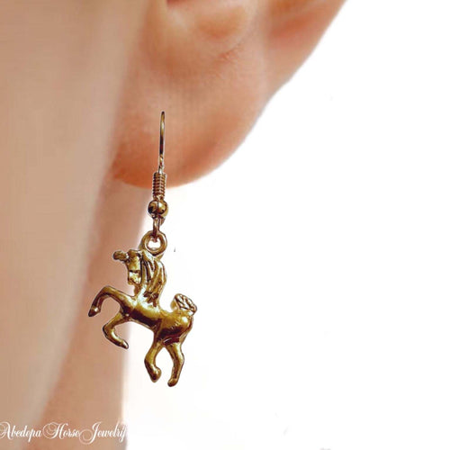 Gold unicorn hook style earrings - with antique design, dangling from ear.