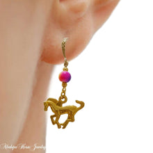 Gold toned rainbow horse earrings with cantering horse design and ceramic bead.