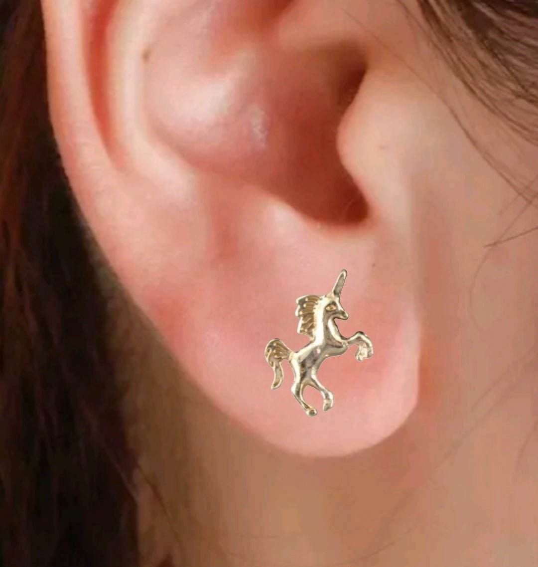 Tiny gold unicorn studs on ear, dainty and delicate design.