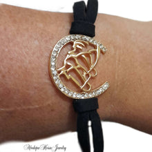 Gold horse head bracelet with crystals and black cord.